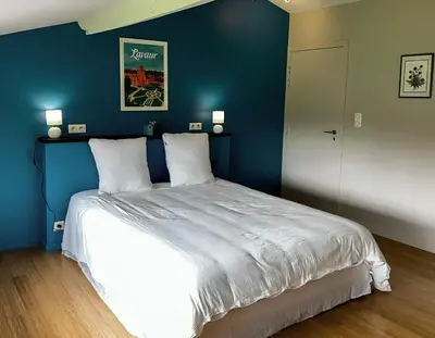 a bedroom with a large bed with a blue wall at Domaine du Léou in Fiac