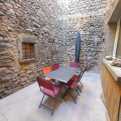 a table and chairs on a patio with a stone wall at Le chant des vignes - Maison pour 6 avec patio in Aigne