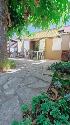 a patio with a table and chairs under a tree at pavillon 45m2, 2 Chambres, 1 salon cuisine, 1sdb in Gruissan