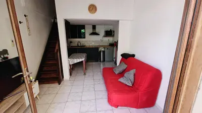 a red couch in a living room with a kitchen at pavillon 45m2, 2 Chambres, 1 salon cuisine, 1sdb in Gruissan