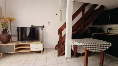 a living room with a tv and a desk with a table sidx sidx at pavillon 45m2, 2 Chambres, 1 salon cuisine, 1sdb in Gruissan