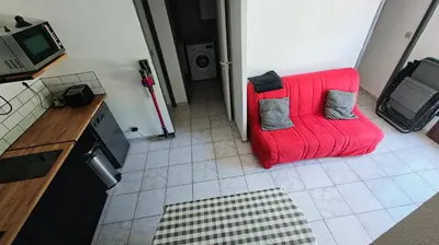 a red couch sitting in the middle of a kitchen at pavillon 45m2, 2 Chambres, 1 salon cuisine, 1sdb in Gruissan