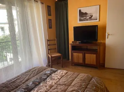 a bedroom with a bed and a tv and a window at Charmante maison à la montagne in Belcaire