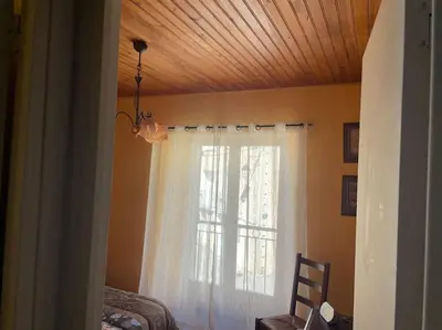 a bedroom with a window with a white curtain at Charmante maison à la montagne in Belcaire