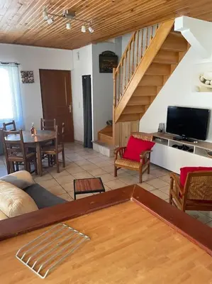 a living room with a staircase and a table and chairs at Charmante maison à la montagne in Belcaire