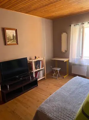 a bedroom with a bed and a television and a desk at Charmante maison à la montagne in Belcaire