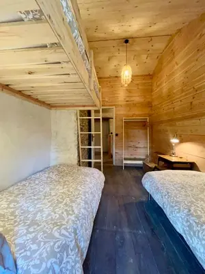 two beds in a room with wooden walls at Parenthèse en Forêt - Gîte Hautbois, Sidobre in Le Bez