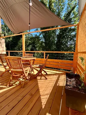 a wooden deck with a table and chairs on it at Parenthèse en Forêt - Gîte Hautbois, Sidobre in Le Bez