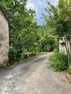 a dirt road next to a house and trees at Parenthèse en Forêt - Gîte Hautbois, Sidobre in Le Bez