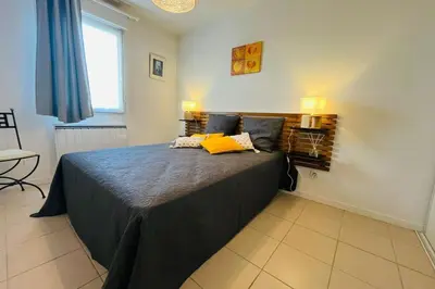 a bedroom with a bed with a yellow pillow on it at Le Rimini Terrasse Wifi Parking privé in Narbonne