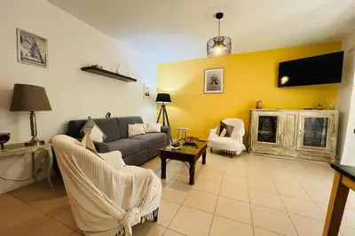 a living room with a couch and a tv at Le Rimini Terrasse Wifi Parking privé in Narbonne