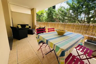 a patio with a table and chairs and a fence at Le Rimini Terrasse Wifi Parking privé in Narbonne
