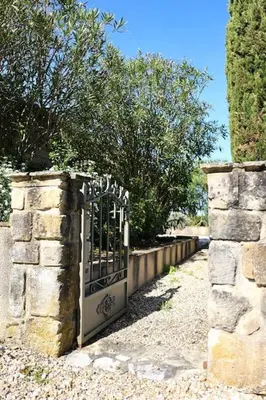 a gate in a stone wall with trees in the background at Gîte Les Tilleuls in Lautrec