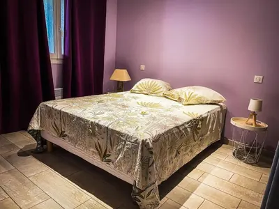 a bed in a bedroom with a purple wall at Appartement 1 chambre in Peyriac-de-Mer