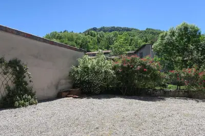 a garden with bushes and flowers next to a building at Le gîte de Melly in Bélesta