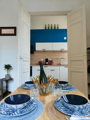 a table with blue and white plates and a bottle of wine at Will's Appart in Narbonne