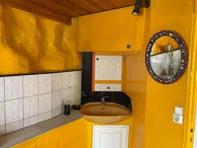 a yellow bathroom with a sink and a mirror at La bergerie des étoiles in Rouvenac