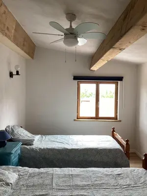 a bedroom with two beds and a ceiling fan at La Biste in Mirepoix