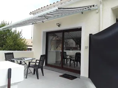 a patio with a glass door with chairs and a table at Grand studio au milieu des vignes in Moussan