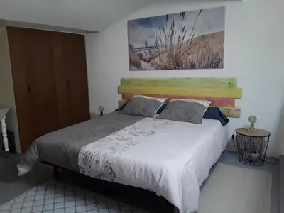 a bedroom with a white bed with a wooden headboard at Grand studio au milieu des vignes in Moussan
