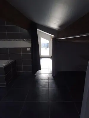 a dark bathroom with a window and a tiled floor at T3 Terrasse vue Cathédrale Climatisé in Narbonne