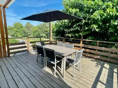 a table and chairs with an umbrella on a deck at L'Onde des berges de l'Aude in Carcassonne