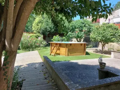 a wooden table in the middle of a garden at L'Onde des berges de l'Aude in Carcassonne