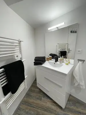 a white bathroom with a sink and a mirror at La detente in Lézignan-Corbières