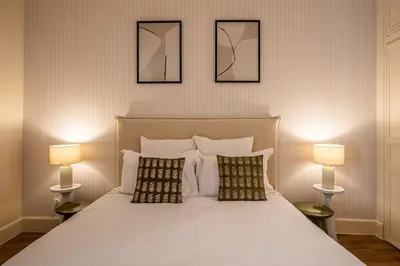 a bedroom with a large white bed with two lamps at L'Impérium Suite - Les Halles - Narbonne in Narbonne