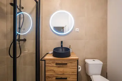 a bathroom with a sink and a shower with a mirror at L'Impérium Suite - Les Halles - Narbonne in Narbonne