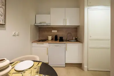 a small kitchen with white cabinets and a table at L'Impérium Suite - Les Halles - Narbonne in Narbonne