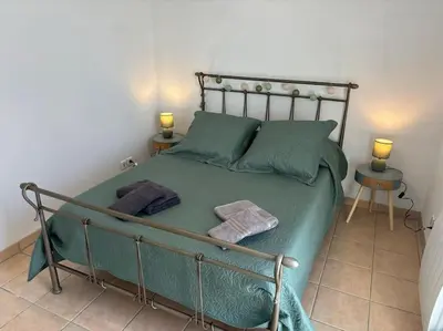 a bedroom with a bed with green sheets and two lamps at L'Escapade Cathare - Résidence Terrasse & parking in Carcassonne