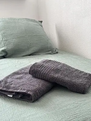 a purple blanket laying on a bed next to a pillow at L'Escapade Cathare - Résidence Terrasse & parking in Carcassonne