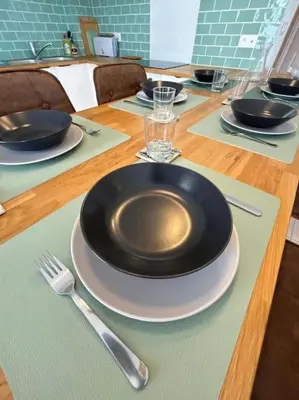 a table with plates and utensils on a wooden table at L'Escapade Cathare - Résidence Terrasse & parking in Carcassonne