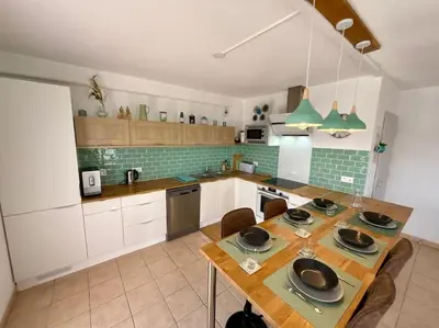 a kitchen with a wooden table with chairs and green tiles at L'Escapade Cathare - Résidence Terrasse & parking in Carcassonne