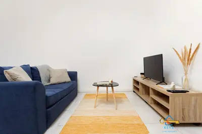 a living room with a blue couch and a tv at Le cocon centre ville au calme Oc Keys 34 in Castelnaudary
