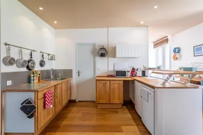 a kitchen with white walls and wooden cabinets at Hypercentre - Proche Parking Gratuit - Fibre - Calme in Narbonne