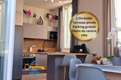 a kitchen with white cabinets and a table with chairs at L'Orchidée, proche de la gare avec clim et terrasse in Narbonne