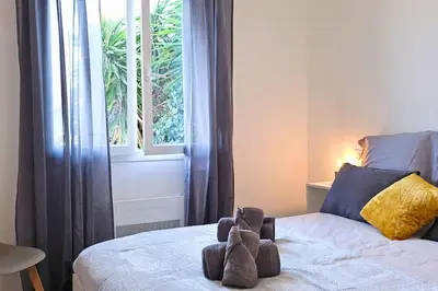 a stuffed animal sitting on top of a bed at L'Orchidée, proche de la gare avec clim et terrasse in Narbonne