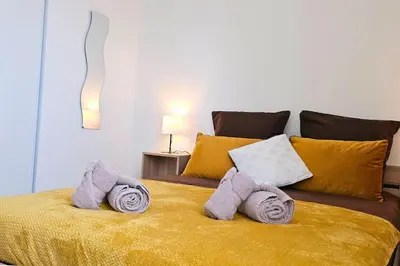 a bedroom with a yellow bed with towels on it at L'Orchidée, proche de la gare avec clim et terrasse in Narbonne