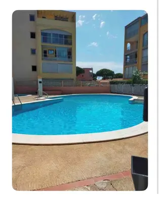 a large blue swimming pool in front of a building at Superbe 2 pièces climatisé avec piscines in Gruissan
