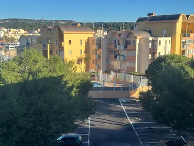 a bridge over a parking lot in front of buildings at Superbe 2 pièces climatisé avec piscines in Gruissan