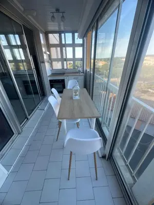 a table and chairs in a room with large windows at Superbe 2 pièces climatisé avec piscines in Gruissan