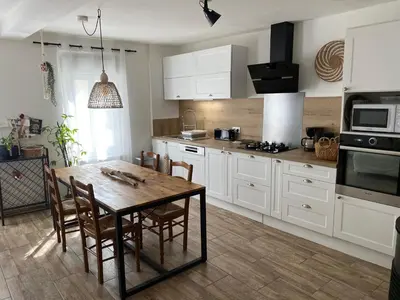 a kitchen with white cabinets and a wooden table at Casa Bohème in Saint-Jean-de-Barrou