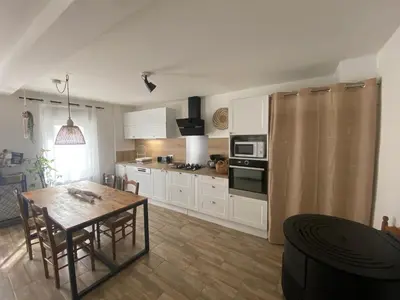 a kitchen with a wooden table and a dining room at Casa Bohème in Saint-Jean-de-Barrou
