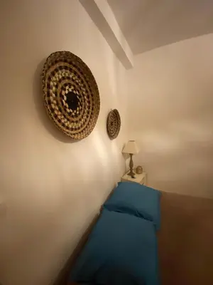 a bedroom with a blue bed and a wall with a hat at Casa Bohème in Saint-Jean-de-Barrou
