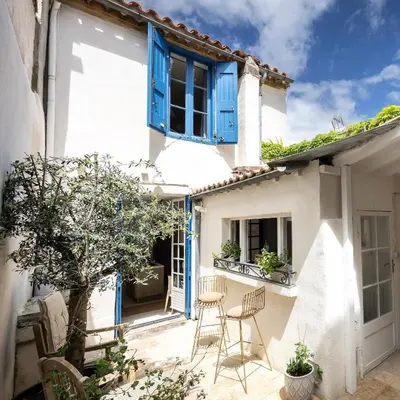 a white house with blue windows and chairs on a patio at Carcassonne Epicerie in Carcassonne