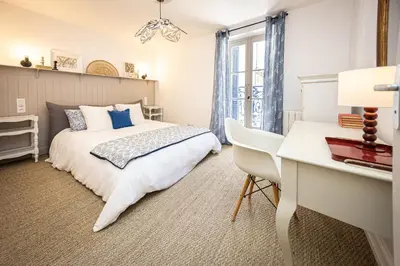 a bedroom with a white bed and a desk at Carcassonne Epicerie in Carcassonne