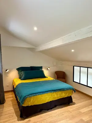a bedroom with a bed with a blue and yellow blanket at Maison Jasmin in Gruissan