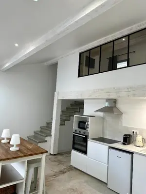 a kitchen with white cabinets and a staircase at Maison Jasmin in Gruissan